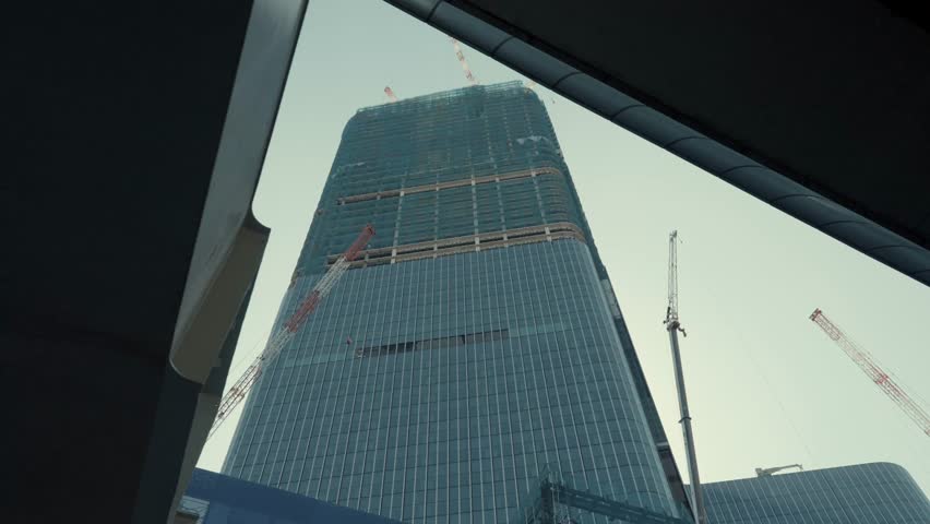 Ground-up view of a skyscraper under construction in Tokyo, featuring towering cranes, steel framework, and modern engineering. Capturing urban development, architecture, and the city