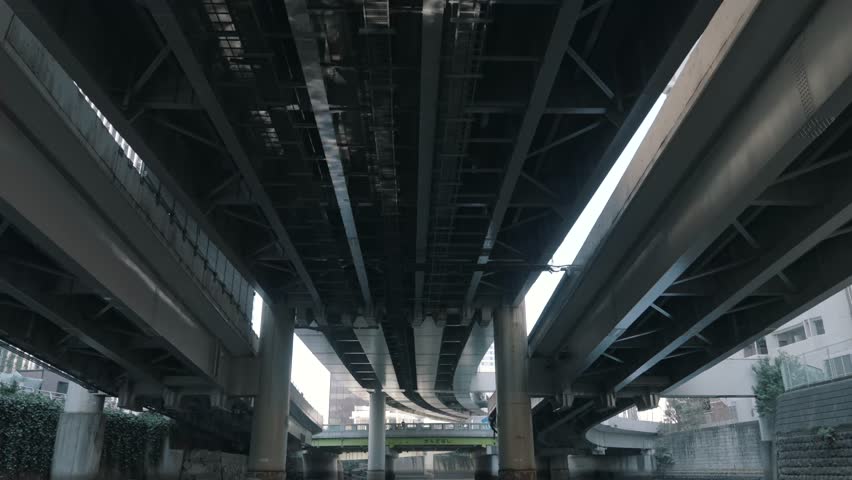 Underneath view of a massive bridge, highlighting its structural design, steel framework, and engineering details. Capturing urban infrastructure, construction, and architectural significance