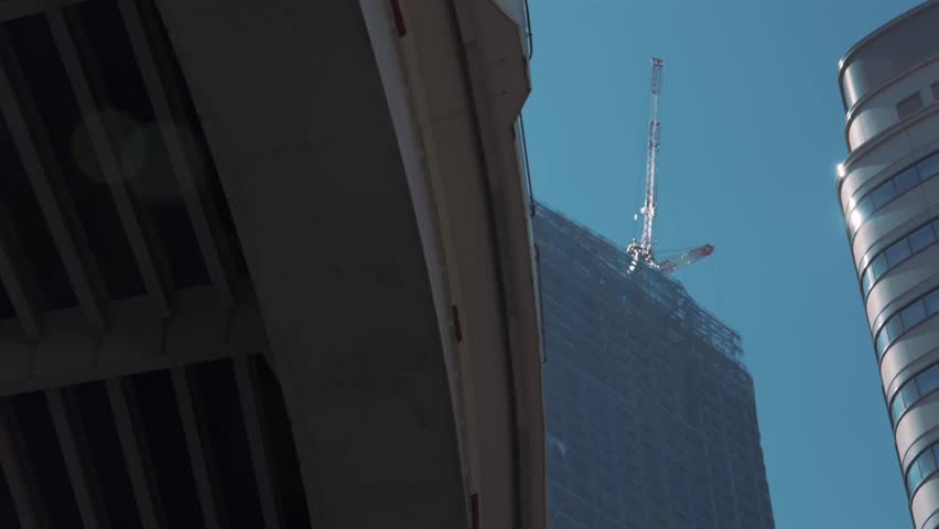 Ground-up view of a skyscraper under construction in Tokyo, featuring towering cranes, steel framework, and modern engineering. Capturing urban development, architecture, and the city