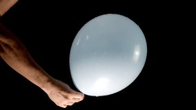 A light blue balloon is popped by a pair of scissors held in a white hand, creating a sharp, dramatic moment. The background footage enhances the visual, bringing focus to the balloon's sudden burst. - Powered by Shutterstock - Get 15% off with code: PIKWIZARD15