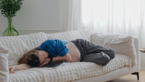 A tired pregnant woman napping on the couch in the living room - Powered by Shutterstock - Get 15% off with code: PIKWIZARD15