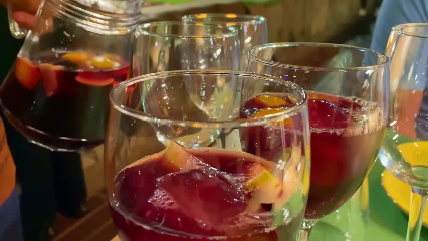 Sangria poured into glass at restaurant table. Close up. Slow motion.