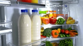 The interior of a fridge filled with colorful vegetables, juice, water and bottles of milk - Powered by Shutterstock - Get 15% off with code: PIKWIZARD15