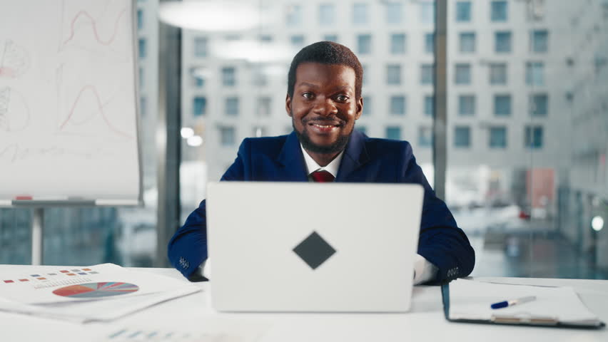 Work day in office, successful businessman opening laptop and working alone. Portrait of African American male person with computer in workplace, co-working area for professionals and freelancers