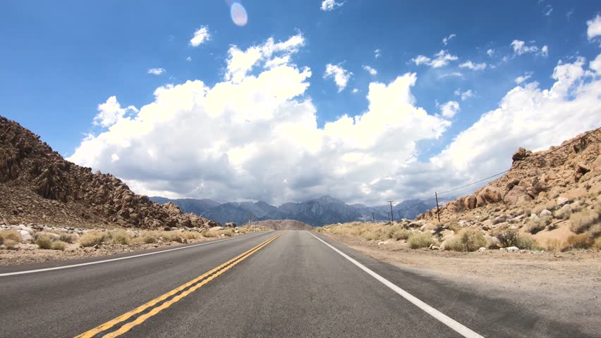 Front Facing Driving Plate Nevada Desert Western American Highway. Day Time Remote No Cars on Road. Bright Sun Blue Sky Clouds