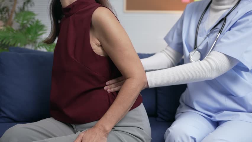 Experienced physiotherapist performing detailed spine examination, carefully assessing back pain of senior patient within professional medical care setting