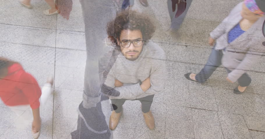 Crouching on sidewalk, man with glasses near bicycle and cyclist passing. Urban, transportation, cycling, eyewear, movement, street