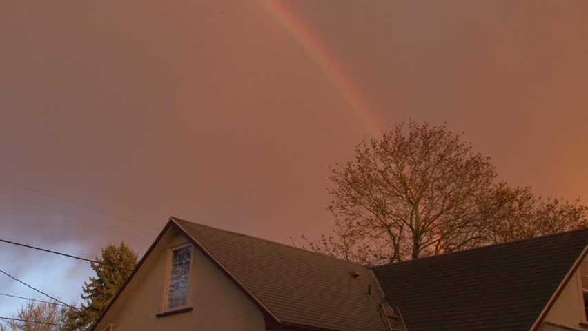 Double rainbow reveals itself over house in neighborhood on rainy, Spring