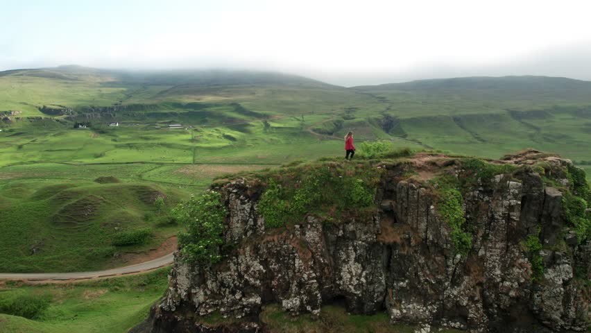 Aerial Drone Adventure Girl Walking Fairy Glen Isle of Skye Scotland in Orange Jacket On Rock Mountain