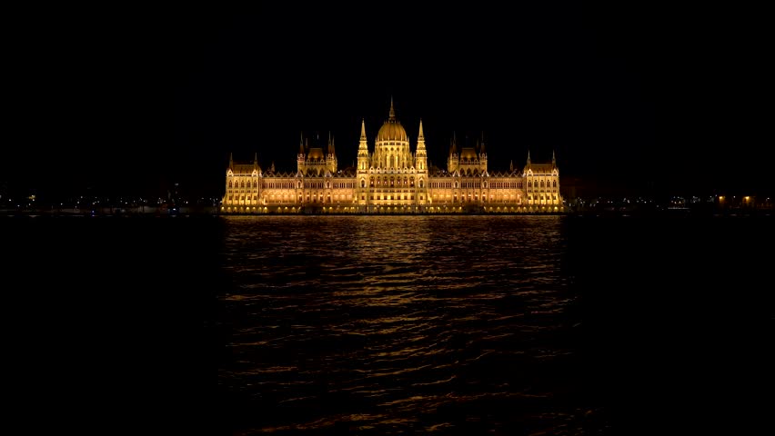 Budapest Parliament Building at Night Lit Up with Warm Lights Over Dark Water Danube River