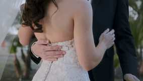 Close-up of the newlyweds at the wedding. Newlyweds hug and touch each other. The bride in a dress with the bride's bouquet, the groom in a suit. Newlyweds in a field at sunset in summer. 4k, 24 fps. - Powered by Shutterstock - Get 15% off with code: PIKWIZARD15