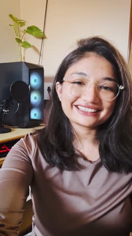 4K Vertical shot of Indian Teenage girl blogger recording vlog video at home and computer CPU in background. Online on social media concept, live streaming. Beautiful woman recording selfie video. 
