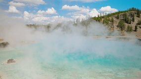 Yellowstone’s hot spring shimmers with bright blue waters, releasing steam into the clear summer sky, creating a mesmerizing geothermal scene. - Powered by Shutterstock - Get 15% off with code: PIKWIZARD15
