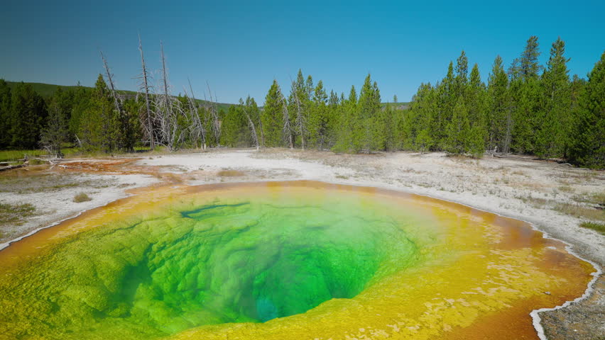 Gazing into Yellowstone’s colorful hot spring, tourists marvel at the vibrant hues and unique geothermal features in this captivating national park attraction.