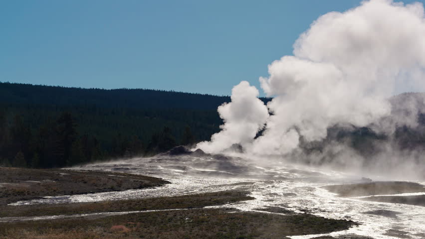 Morning light illuminates Yellowstone’s geysers, as steam fills the air, creating a peaceful and awe-inspiring atmosphere in the park’s geothermal landscape.