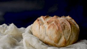 Slow Motion Pan of Freshly Baked Artisan Sourdough Bread – Golden Brown Crust with Scored Pattern Wrapped in Linen Cloth for Food Bloggers and Culinary Visuals - Powered by Shutterstock - Get 15% off with code: PIKWIZARD15