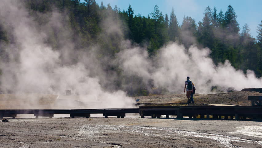 Tourists explore Yellowstone’s amazing geysers and hot springs, walking through the park to witness its breathtaking natural wonders and geothermal features.