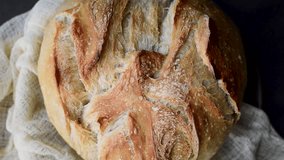 Slow Motion Pan of Freshly Baked Artisan Sourdough Bread – Golden Brown Crust with Scored Pattern Wrapped in Linen Cloth for Food Bloggers and Culinary Visuals - Powered by Shutterstock - Get 15% off with code: PIKWIZARD15