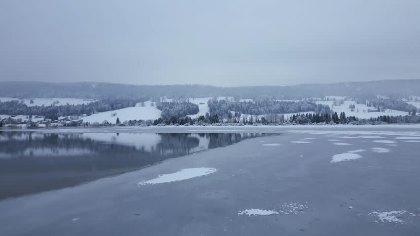Establishing drone shot over frozen Lake of Joux in the winter in Le Chenit, Switzerland