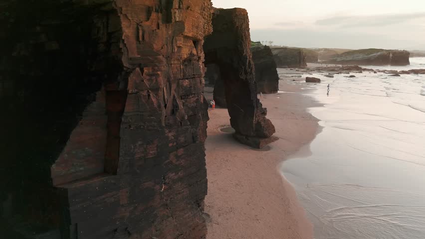 Amazing aerial view of the Playa de Las Catedrales beach in Galicia region at sunset, northern Spain. Beautiful cliff formations on famous Cathedral Beach, Cantabrian Coast 