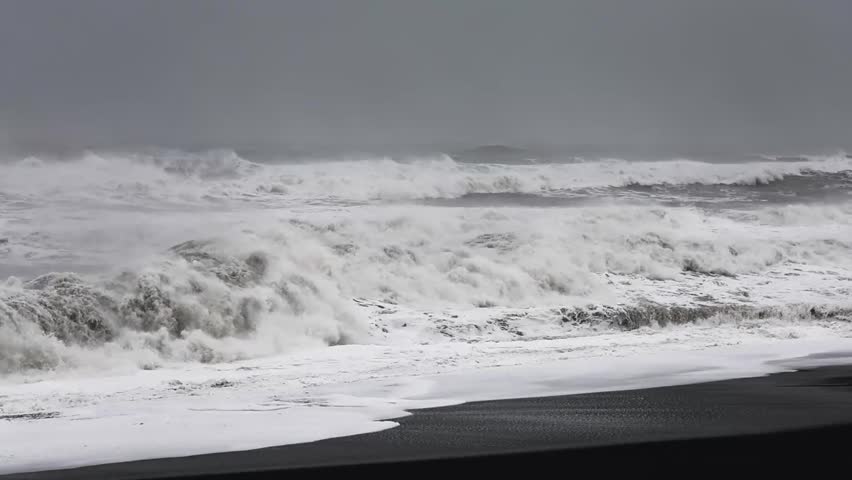 Slow motion of powerful ocean waves crashing on reynisfjara black sand beach in iceland.