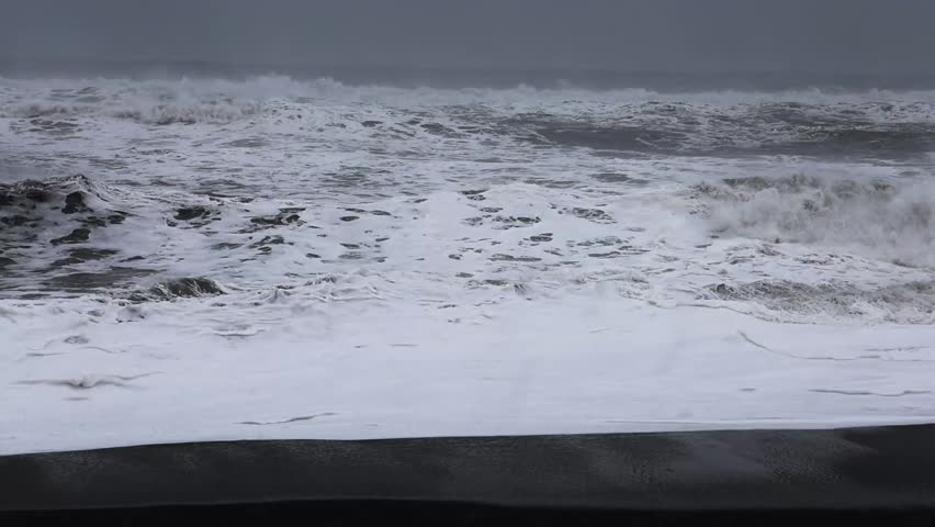 Slow motion of powerful ocean waves crashing on reynisfjara black sand beach in iceland.