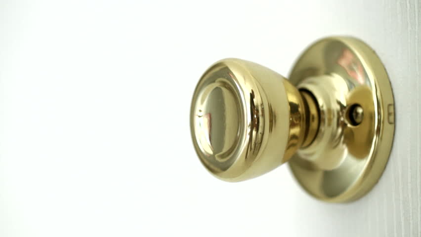 Detail of hands opening and closing a door, with focus on the brass door handle.