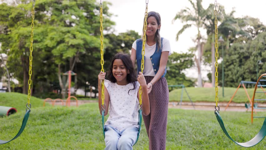 Family time, Happy mother and child having fun on swing set at kids park