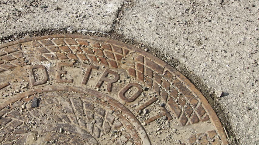 Close up of feet in nice business shoes walking over a grit-covered manhole