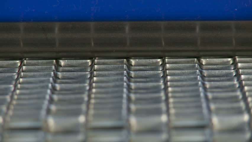 Close up on an industrial conveyor belt with a steel roller visible. Loopable