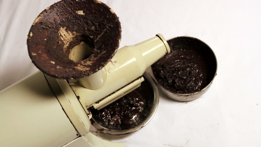 Putting cocoa nibs through a juicer to make liquid chocolate. High view over the