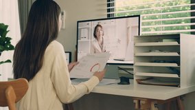 Asian businesswoman in casual participates in an online business meeting, reviewing financial documents while watching a professional presentation on her computer. - Powered by Shutterstock - Get 15% off with code: PIKWIZARD15