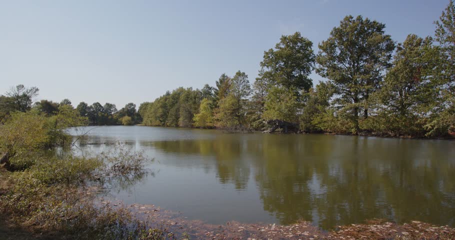 Wide static shot of a lake surrounded by trees in Indiana. Great for backplates, travel, or establishing shots. For projects requiring longer clips in higher resolution, visit StockPlates.