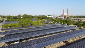 Contrast between old fossil fueld plant and new solar energy panels over parking lot in Michigan, aerial view - Powered by Shutterstock - Get 15% off with code: PIKWIZARD15