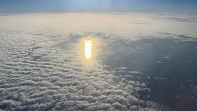 Cumulus clouds above the sea surface backlit and sun reflections on water in a break in the clouds, top view from an airplane side window during a flight at high altitude above of the clouds
 - Powered by Shutterstock - Get 15% off with code: PIKWIZARD15