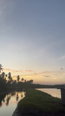 Lake with palm tree silhouettes at sunset under a vibrant sky. Peaceful and tranquil evening scene with a serene atmosphere.