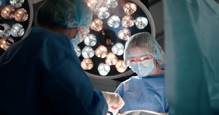 Female surgeon and assistant working together in modern operating room. Focused medical professionals in sterile environment highlighting teamwork and precision during surgical procedure.
