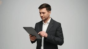 Man in in a suit smiles while using a tablet in a neutral setting, showing engagement. - Powered by Shutterstock - Get 15% off with code: PIKWIZARD15