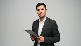 Man in in a suit smiles while using a tablet in a neutral setting, showing engagement. - Powered by Shutterstock - Get 15% off with code: PIKWIZARD15