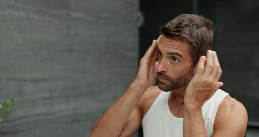 Beard, hair care and man with beauty, mirror and grooming with treatment for shine. House, reflection and person with skincare, hygiene and maintenance with health spa facial, aesthetic and bathroom