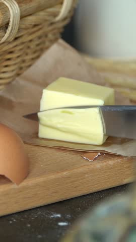 Close up of kitchen knife cut butter on background of rustic products. Natural farm food. Vertical shot