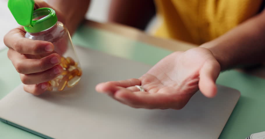 Person, hands and pills with oil for omega, multivitamin or health supplement on table at home. Closeup, patient or capsules with medical diagnosis for pharmaceutical drug, antibiotic or wellness