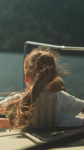Calm girl and boy straighten arms to sides sailing on motorboat on sea on sunny day. Siblings relax enjoying stunning view in summer. Observing beauty of nature