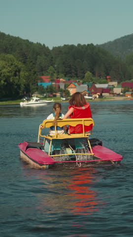 Young mother and little child ride catamaran on lake. Family vacation at reservoir slow motion. Active entertainment on warm summer day backside view