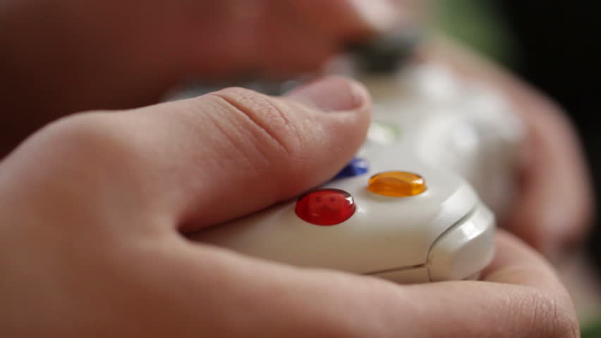 Teenage hands operating a video game controller, close detail view.