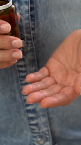 Close up of female hands open jar and pour out pills into palm. Pills and drugs medicament vitamins. Take medicine take pill. Medicine and health care. Vertical shot