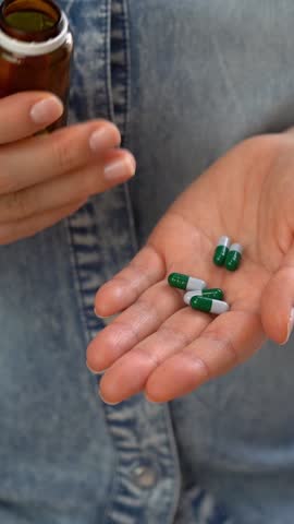 Close up of female hands open jar and pour out pills into palm. Pills and drugs medicament vitamins. Take medicine take pill. Medicine and health care. Vertical shot