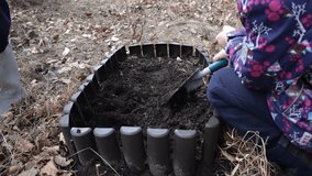 An elementary aged girl dig a hole in a raised garden bed for plant vegetables or flowers.  Basics of growing vegetables in a community garden. Springtime - Powered by Shutterstock - Get 15% off with code: PIKWIZARD15