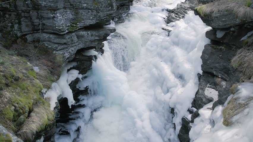 Majestic Winter Rapids – Waterfall Flowing Amidst Ice and Snow