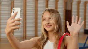 Caucasian little girl holding mobile phone smartphone blogger influencer video call online child kid schoolgirl school sport gym waving hand greeting vlog daughter app conference gymnast hoop student - Powered by Shutterstock - Get 15% off with code: PIKWIZARD15